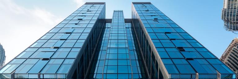 Edificio gubernamental moderno e imponente con fachada de cristal y acero, reflejando el cielo.
